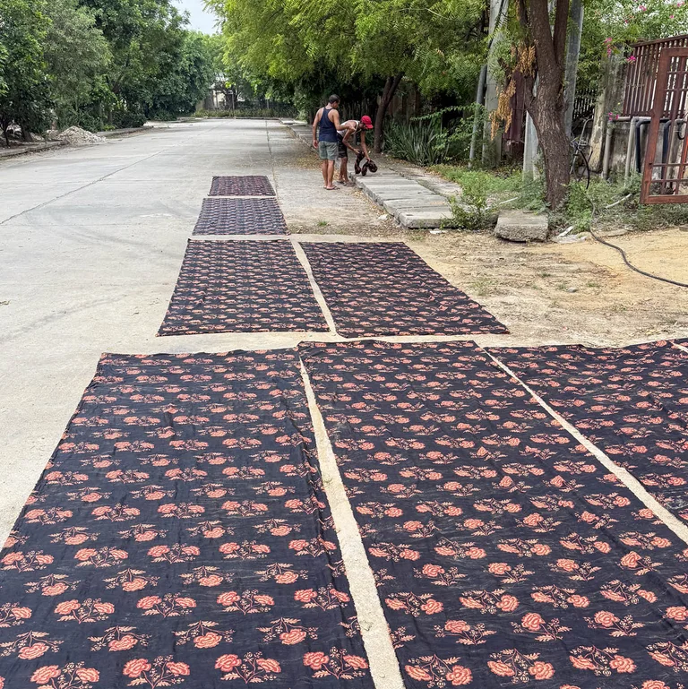 Long lengths of block-printed cloth drying outdoors on the ground in India.