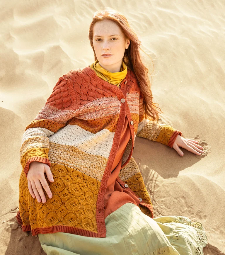 A woman wearing an orange knit cardigan from Gudrun Sjödén. 