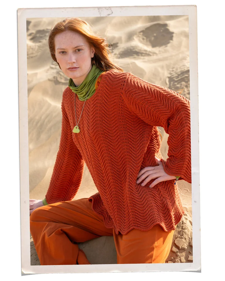 A woman wearing a knit orange sweater from Gudrun Sjödén. 