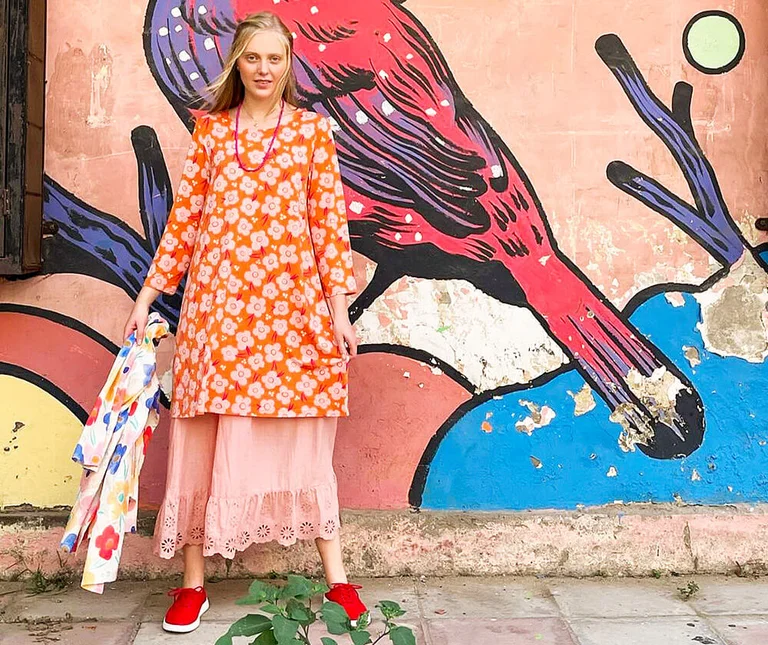 A woman wearing a floral dress from Gudrun Sjödén with street art in the background. 