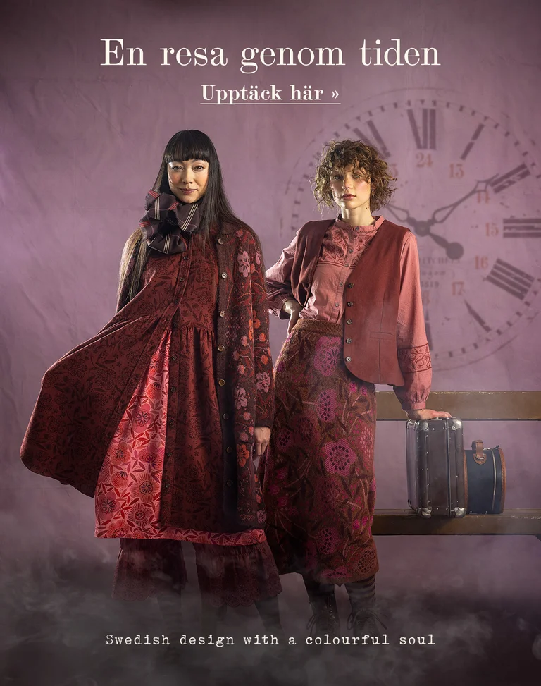 En kvinna som sitter på en stol mot en lila bakgrund, iklädd kläder från Gudrun Sjödén och med en liten resväska i handen.