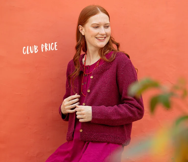 A picture of a woman wearing a dark pink cardigan over a pink dress from Gudrun Sjödén.