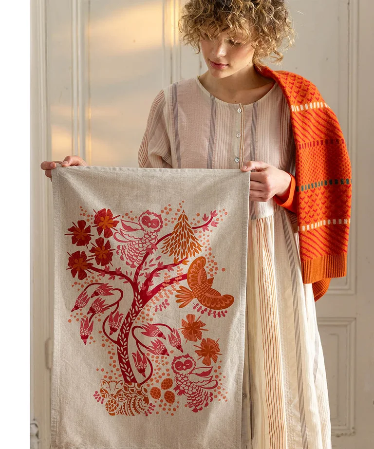 A woman holding a patterned tea towel from Gudrun Sjödén’s 2025 Christmas Home collection.