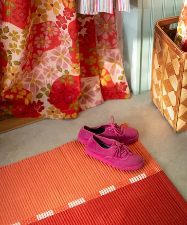 A hall with soft furnishings in shades of orange and red from Gudrun Sjödén.