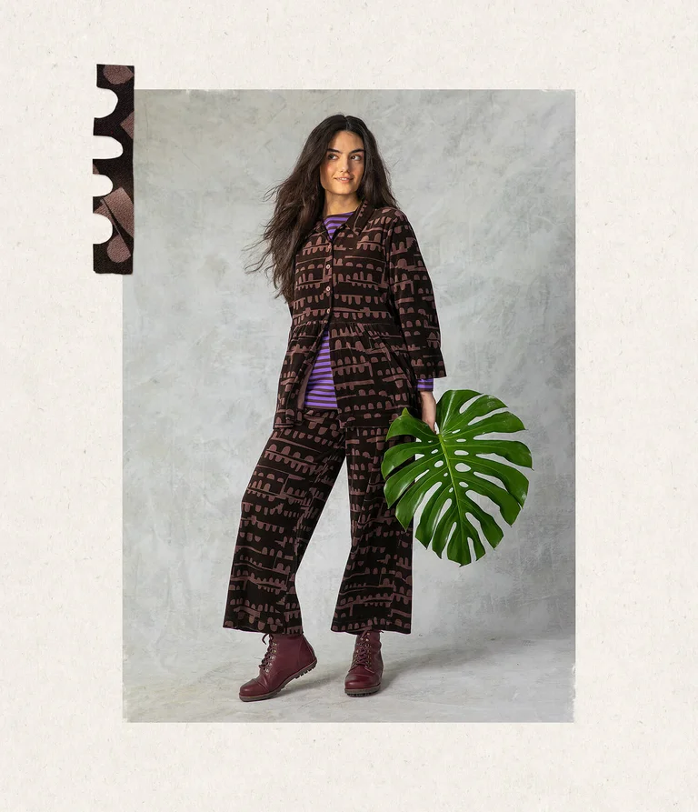 A woman wearing a patterned velour cardigan and velour trousers from Gudrun Sjödén.
