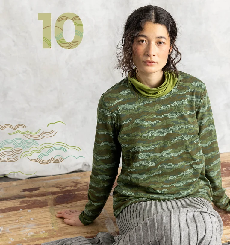 Une femme portant un top vert à motif signé Gudrun Sjödén.