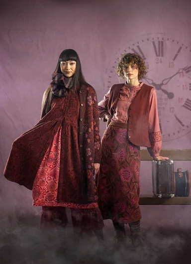 Two women next to each other wearing clothes in shades of red from Gudrun Sjödén.