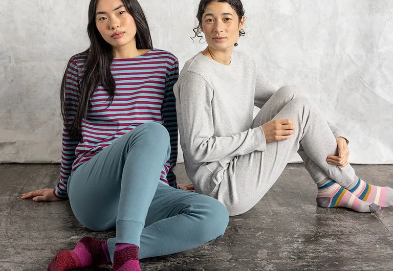 Two seated women modelling clothes from Gudrun Sjödén’s Essentials collection. 