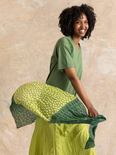 Hands holding a pair of yellow-green sandals from Gudrun Sjödén. 