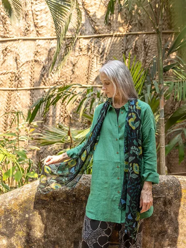 A woman wearing a green shirt and patterned scarf from Gudrun Sjödén.