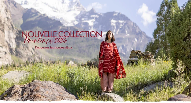 Une femme se tenant dans un paysage montagneux et portant des vêtements rouges tissés signés Gudrun Sjödén.