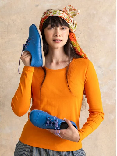 A woman on a beach with a purple shawl from Gudrun Sjödén around her shoulders.