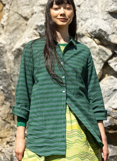 A woman wearing a green striped shirt from Gudrun Sjödén.