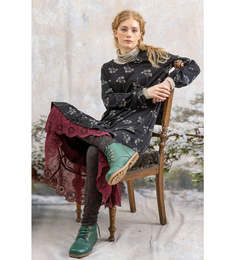 Eine Frau in gemustertem Kleid und Leggings von Gudrun Sjödén.