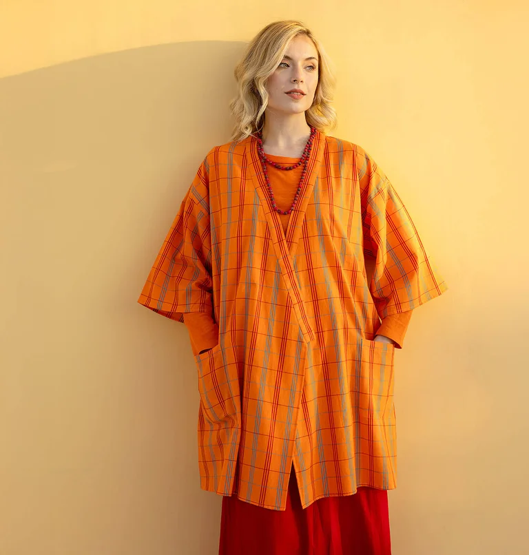 Eine Frau in einem karierten orangefarbenen Kimono von Gudrun Sjödén.
