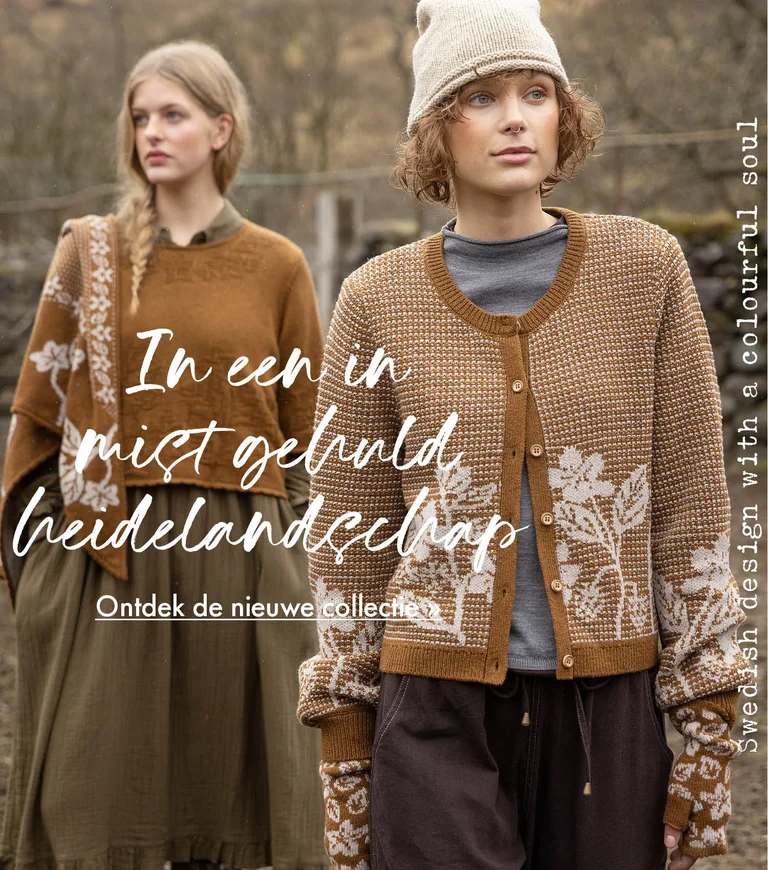 Two women standing next to each other wearing clothes in earthy hues from Gudrun Sjödén. Sheep and a stone wall are visible in the background.