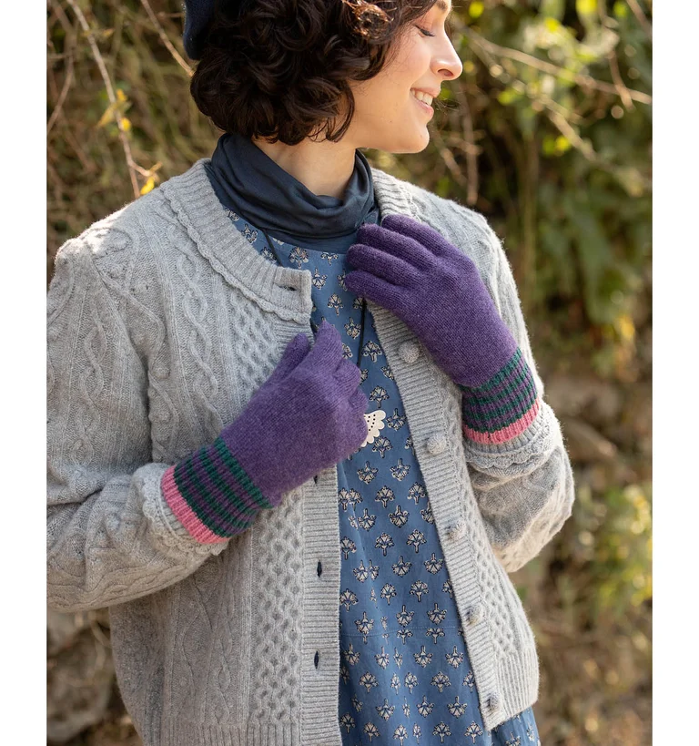 Une femme portant un gilet gris en maille torsadée signé Gudrun Sjödén.