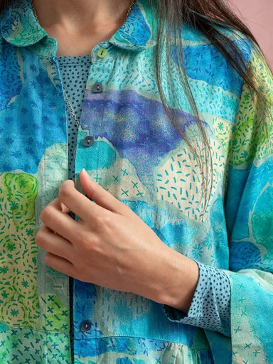 An upper body wearing layers of patterned clothes from Gudrun Sjödén.