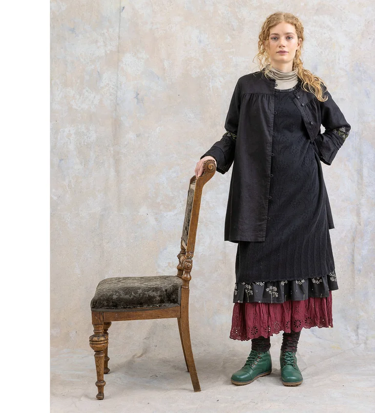 Eine Frau in schwarzer Tunika und Strickkleid von Gudrun Sjödén.