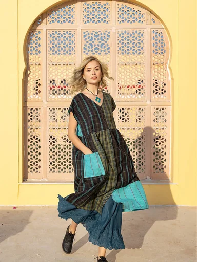 Une femme portant un gilet color block aux couleurs joyeuses signé Gudrun Sjödén.