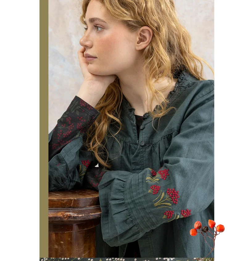 Eine Frau in einer bestickten Bluse von Gudrun Sjödén.