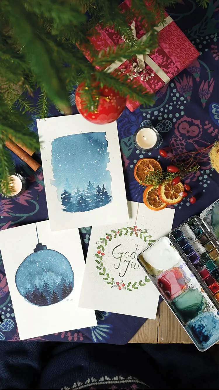 Handen schilderen verschillende kerstkaarten met aquarelverf in een kerstsfeer.  