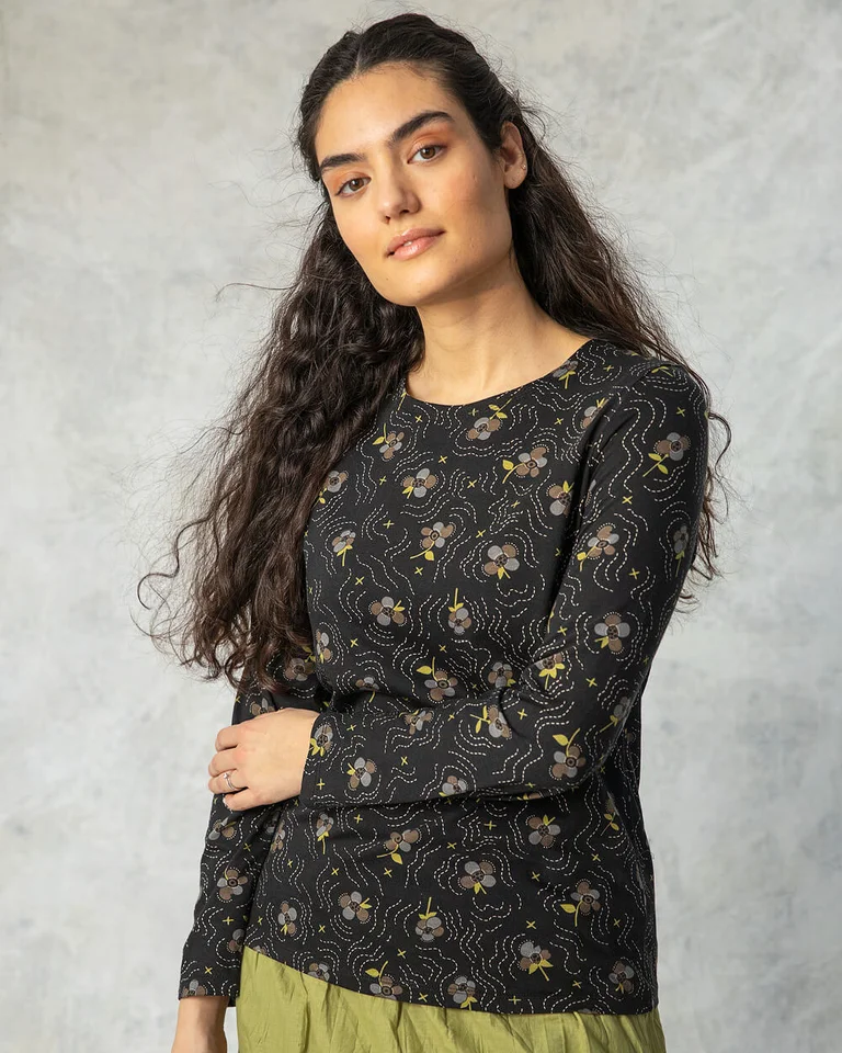 A woman wearing a black floral top from Gudrun Sjödén.