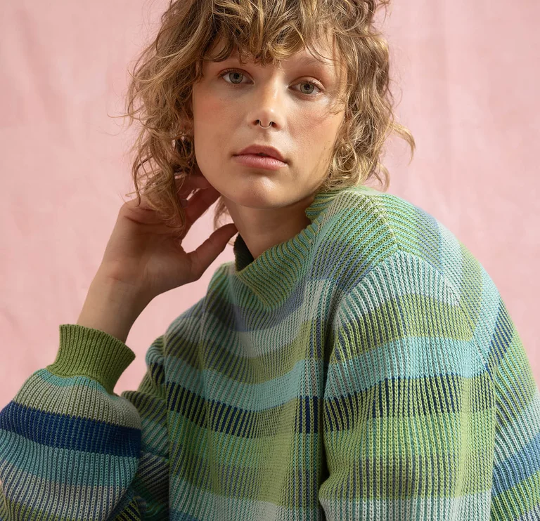 A woman’s face behind green stems. 