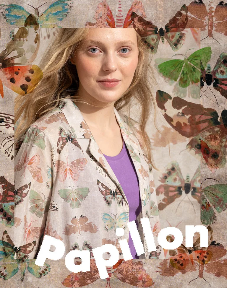 Une femme photographiée devant un arrière-plan de papillons et portant une robe beige au motif de papillons signée Gudrun Sjödén.