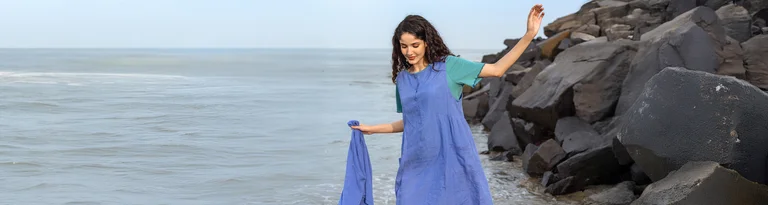 A woman wearing a blue, woven sleeveless dress in linen from Gudrun Sjödén.