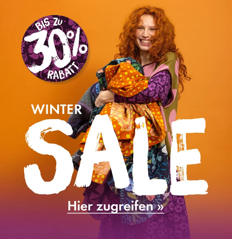 Eine Frau mit farbenfrohen Kleidungsstücken von Gudrun Sjödén im Arm.