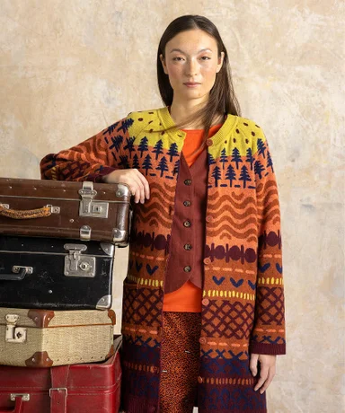 A woman wearing a knitted patterned cardigan in shades of orange and yellow from Gudrun Sjödén.