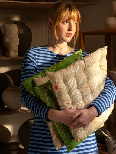 A woman holding seat cushions from Gudrun Sjödén in her arms.