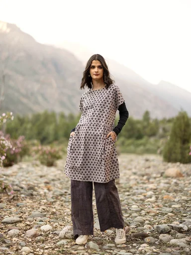 A woman wearing a patterned dress and patterned pants from Gudrun Sjödén. 