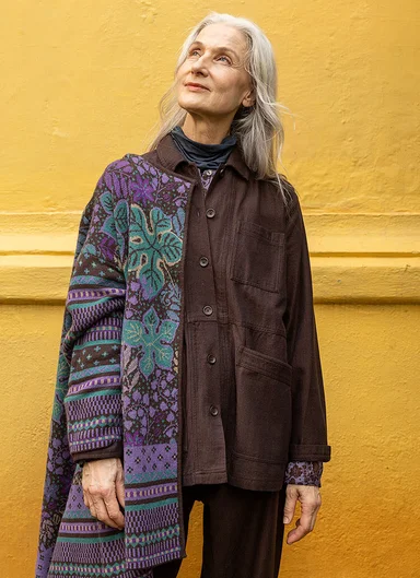 A woman wearing a brown shirt and patterned cardigan from Gudrun Sjödén.