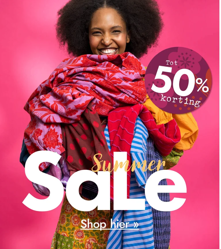 A woman with her arms full of colourful clothes from Gudrun Sjödén.