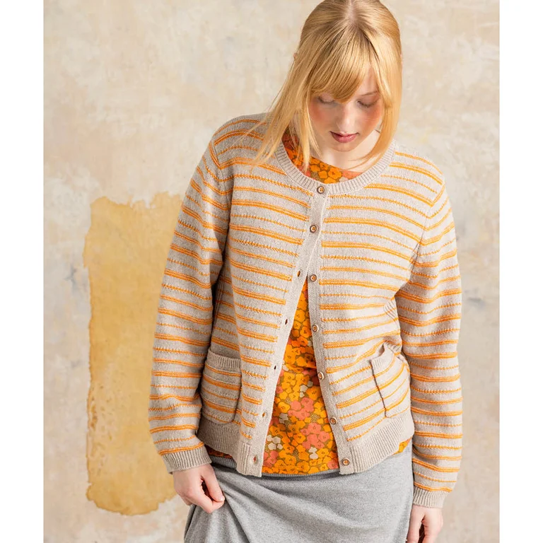 A woman wearing a natural white cardigan with orange stripes over an orange floral top and a grey skirt from Gudrun Sjödén.