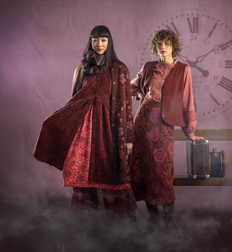 Two women next to each other wearing layers of clothing in shades of red from Gudrun Sjödén.