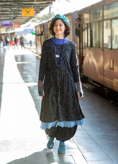A woman boarding a train wearing a long pink down coat from Gudrun Sjödén.