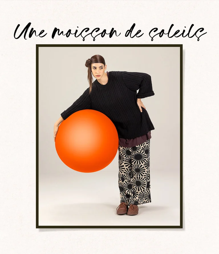 A woman wearing black and white clothing from Gudrun Sjödén, holding a large red ball.