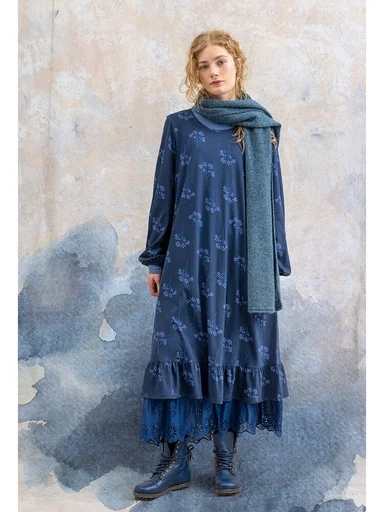 Eine Frau in einem blau gemusterten Kleid von Gudrun Sjödén. 