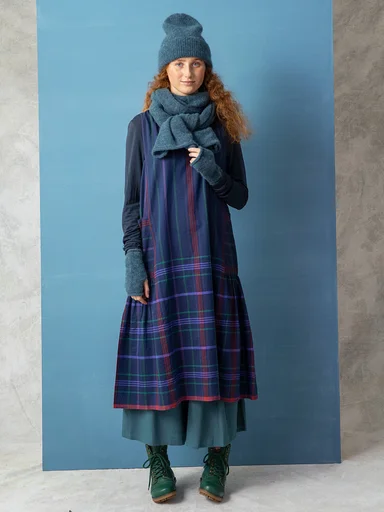 A woman wearing a blue beanie, scarf and fingerless gloves from Gudrun Sjödén.