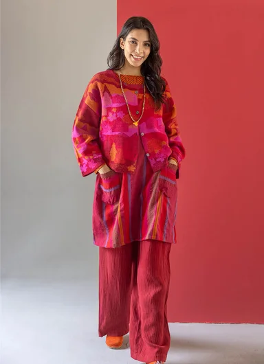 A woman wearing bright pink and red clothes from Gudrun Sjödén’s Alaska Colourful by the Sea collection, posing against a light background.