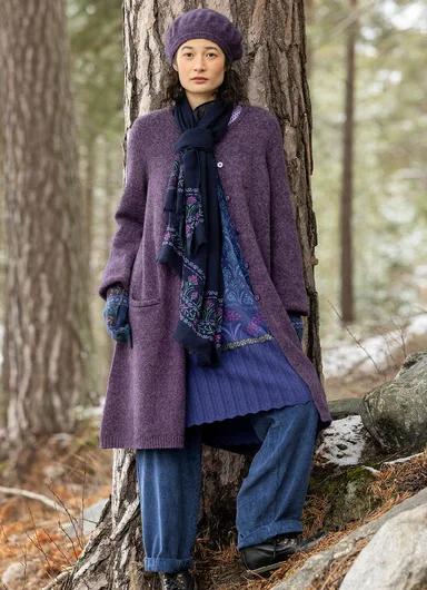 A woman standing in the forest wearing clothes from Gudrun Sjödén. 