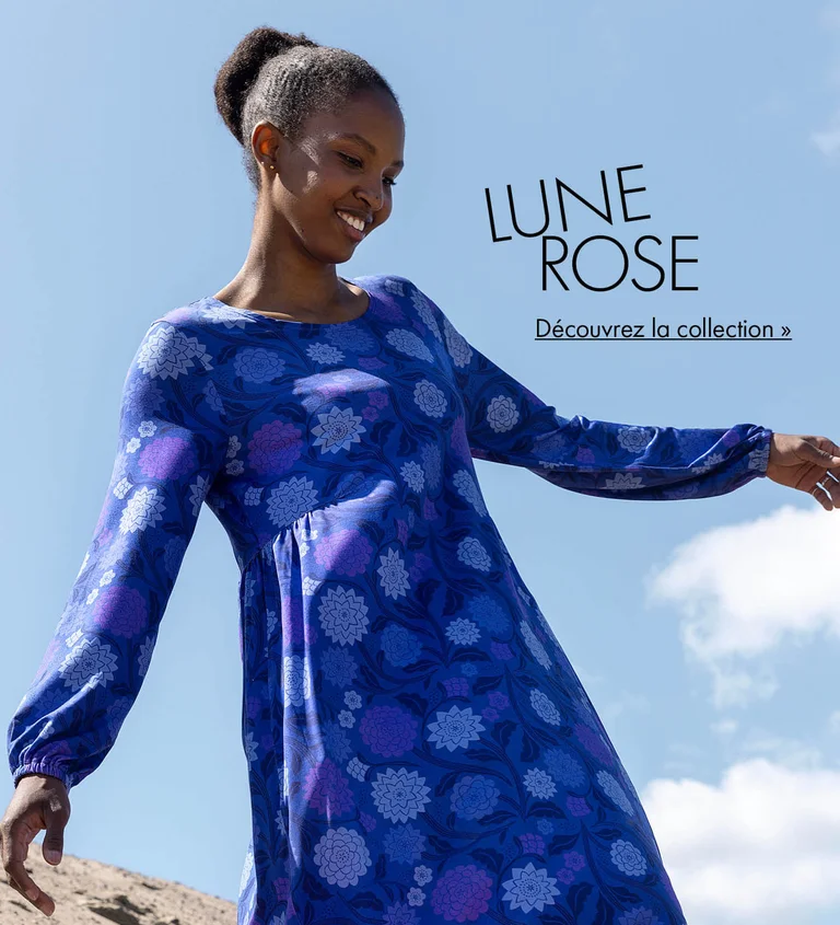 Une femme se tenant à l’extérieur sur fond de ciel bleu et portant une robe bleu-violet à motif signée Gudrun Sjödén.