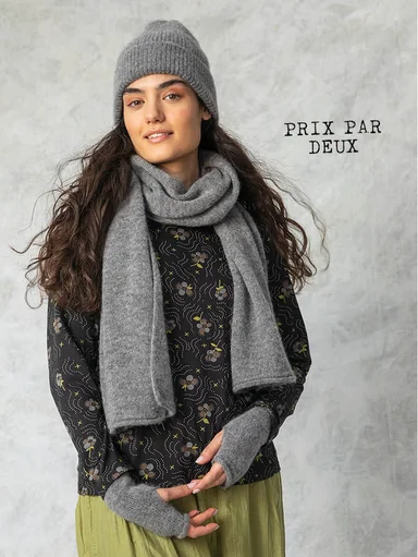 A woman wearing a grey beanie, scarf and fingerless gloves from Gudrun Sjödén.