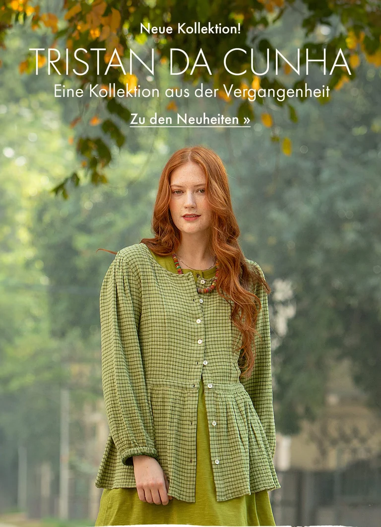 Eine Frau vor grüner Kulisse, in grüner Mode aus Gudrun Sjödéns Winterkollektion 2025. 