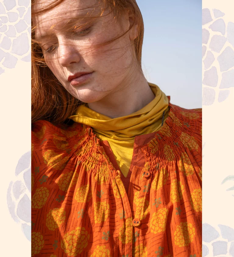 A woman wearing a patterned orange dress from Gudrun Sjödén.