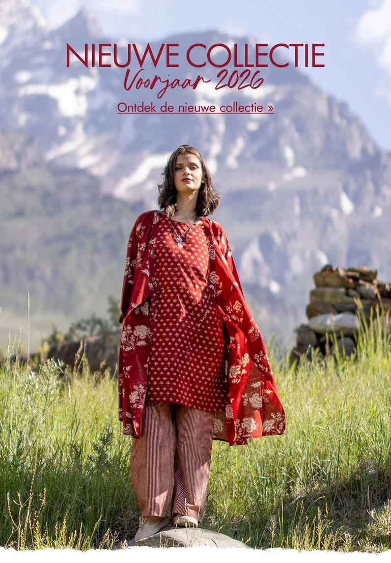 Een vrouw in een berglandschap gekleed in laagjes rode, geweven kleding van Gudrun Sjödén.