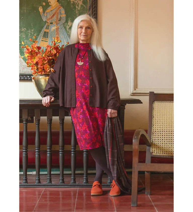 En kvinna iklädd en röd klänning matchad med en brun blus från Gudrun Sjödén.